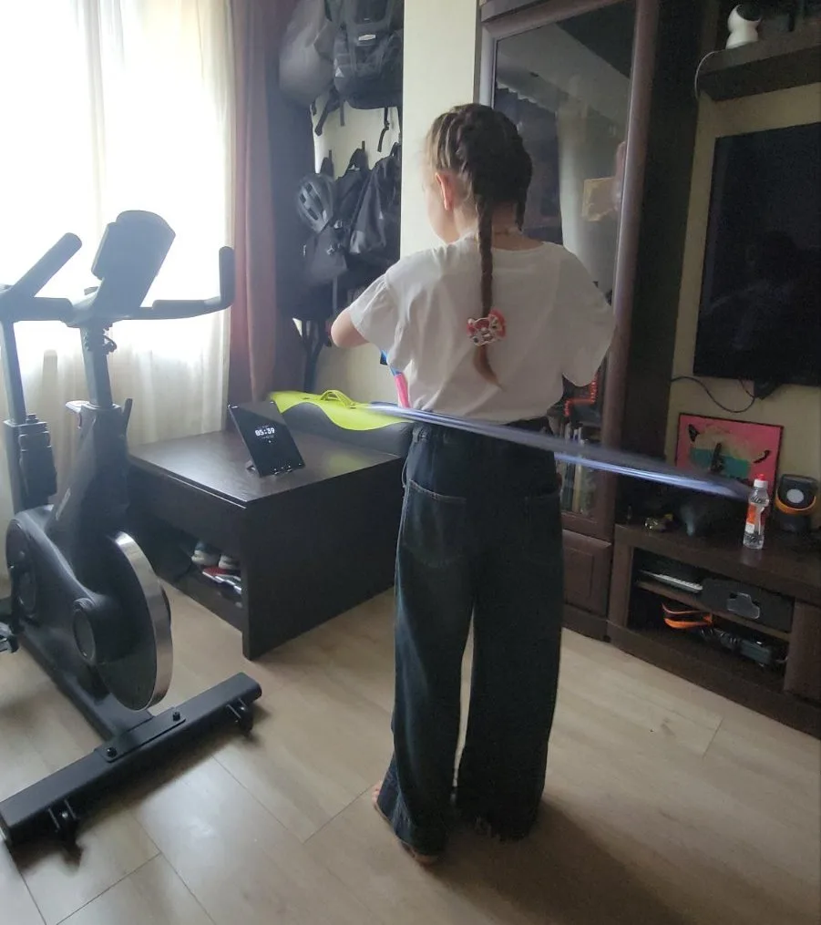 Ein Kind dreht zu Hause einen Hula-Hoop-Reifen, daneben ein Tablet mit VoiceControl Stopwatch — einer sprachgesteuerten Stoppuhr.
